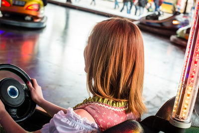 Rear view of woman sitting in bumper car at amusement park