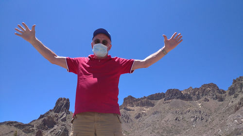 Low angel view of man standing against blue sky