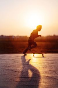 Silhouette man with arms raised against sky during sunset