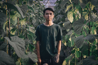 Portrait of young man standing against plants