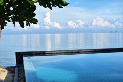 Swimming pool by sea against sky