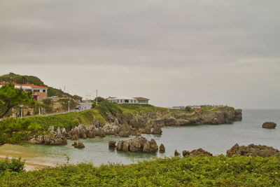 Buildings by sea against sky