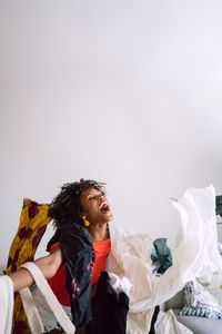 Black woman with afro hair throwing pile of clothing standing in the living room screaming