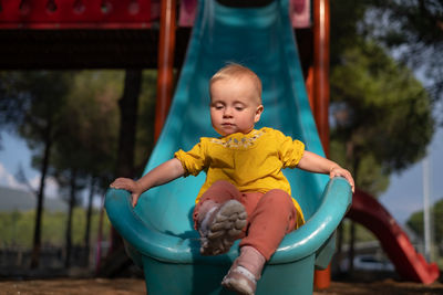 Portrait of boy sitting on slide at playground