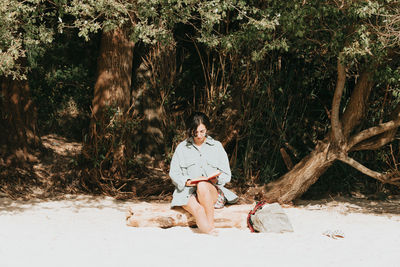 Full length of young woman sitting on land