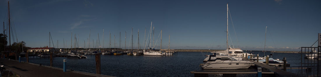 Sailboats moored at harbor against sky