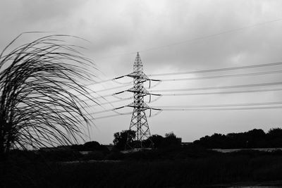 Low angle view of silhouette electricity pylon on field against sky