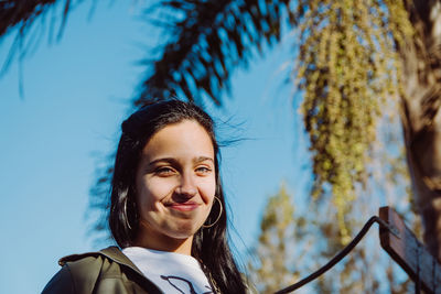 Portrait of a smiling young woman against blue sky