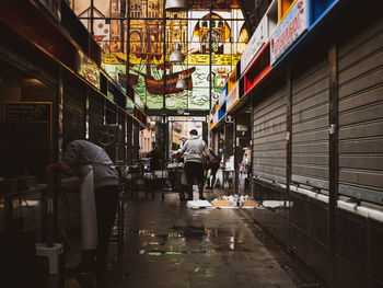 People walking on wet street in city during rainy season