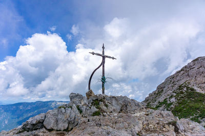 Low angle view of cross on rock against sky