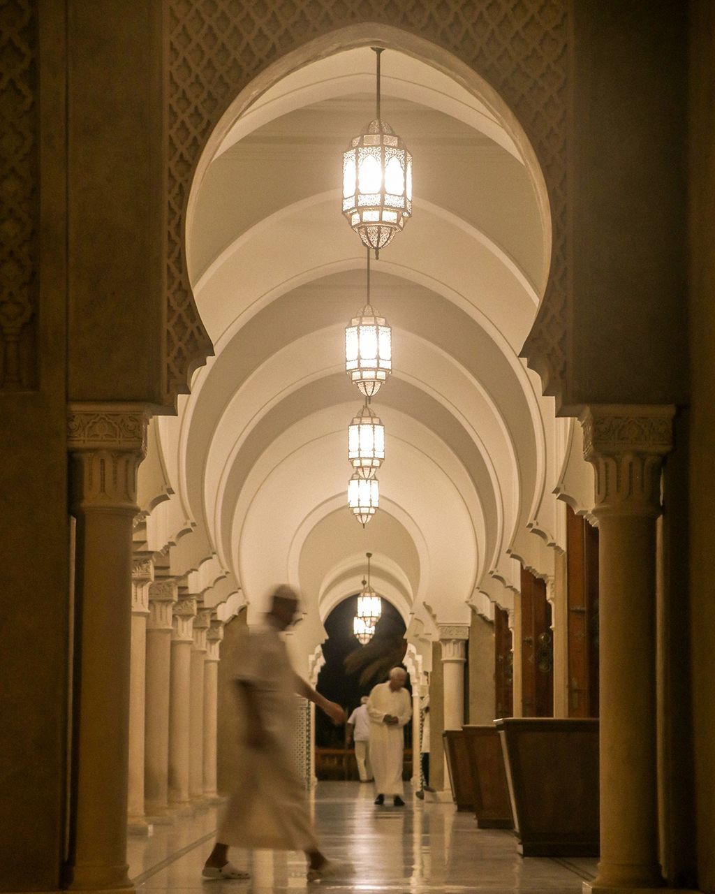 architecture, arcade, arch, built structure, corridor, walking, indoors, illuminated, architectural column, building, men, lighting equipment, real people, motion, in a row, adult, women, people, lifestyles, two people, ceiling, couple - relationship, electric lamp