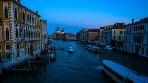 Boats in canal amidst buildings in city
