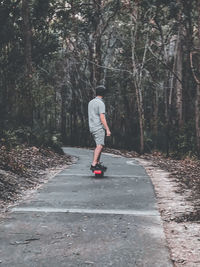 Rear view of man skateboarding on road