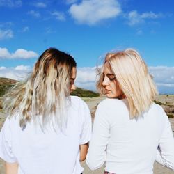 Panoramic shot of friends on landscape against sky