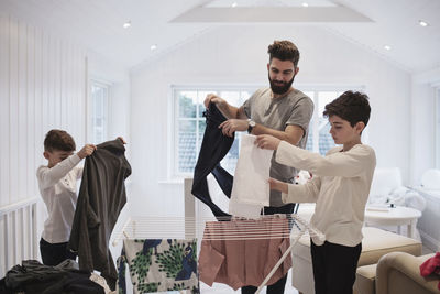 Bearded father with sons drying laundry at home