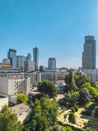 Trees and buildings against clear sky