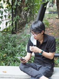 Young man using mobile phone sitting outdoors