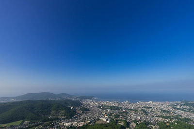 Aerial view of cityscape against clear blue sky