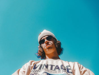 Low angle view of man standing against clear blue sky