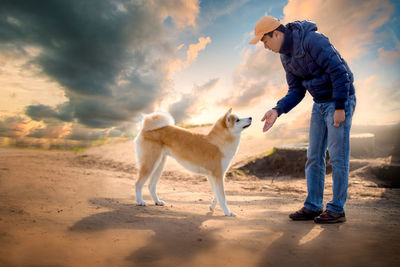 Side view of man with dog against sky