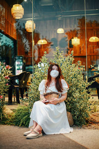 Portrait of young woman standing against trees