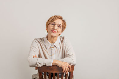 Portrait of young woman sitting against white background