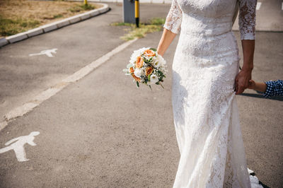 Low section of woman with umbrella walking on road