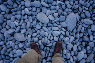 Low section of man standing on pebbles