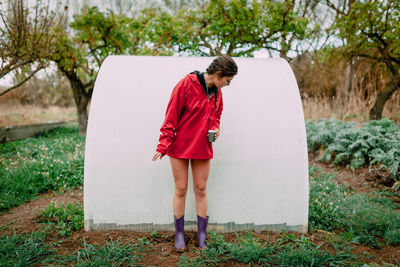 Young woman looking down standing by built structure