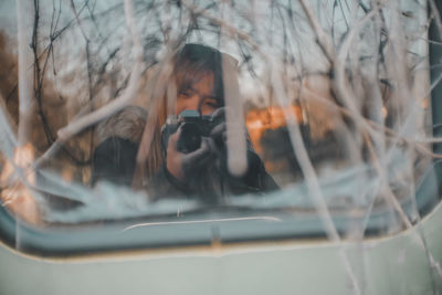 Reflection of woman photographing seen on land vehicle