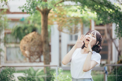 Young woman standing against trees