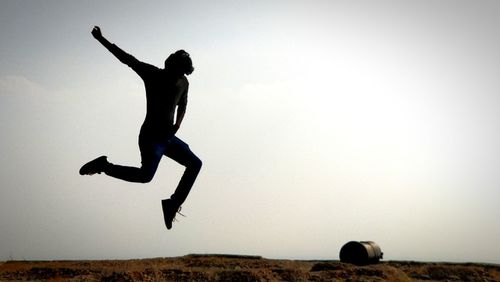 Full length of silhouette man jumping against clear sky