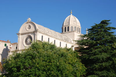 Low angle view of trees and building against sky