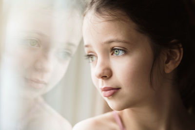 Close-up of girl looking away standing by window