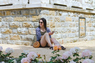 Portrait of young woman sitting against wall