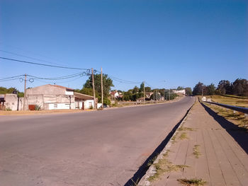 Road against clear blue sky in city