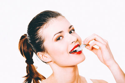 Close-up portrait of woman with hand on white background