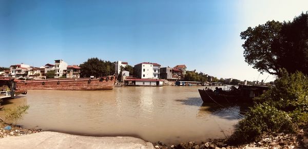 Buildings by river against sky