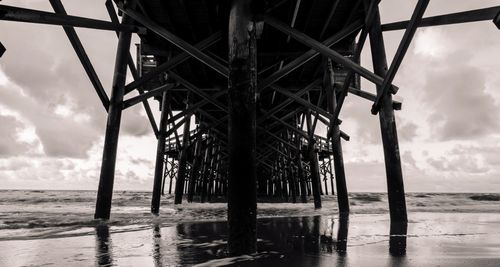 Silhouette of pier on beach against sky