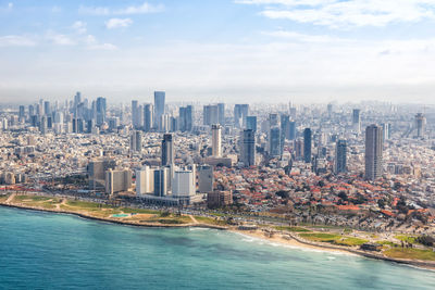 Aerial view of city by sea against sky