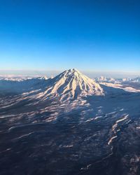 Aerial view of snowcapped mountains against blue sky