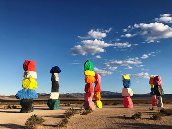 Rear view of people standing at beach against blue sky