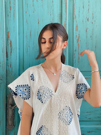 Portrait of young woman standing against wall