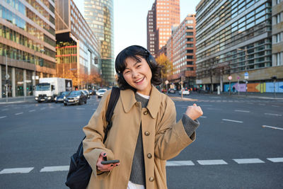 Portrait of young woman standing in city