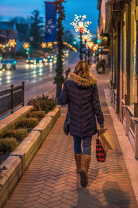 Rear view of woman walking on footpath at night