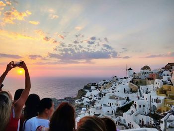 Rear view of people looking at sea during sunset