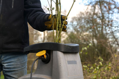 Midsection of man putting plants in machinery outdoors