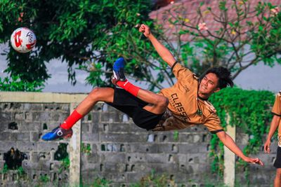 Full length of young man jumping against trees