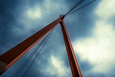 Low angle view of suspension bridge against cloudy sky