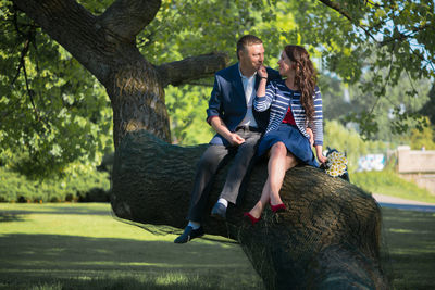 Man and woman sitting on tree trunk at park